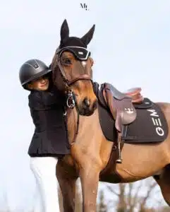 Cheval équipé d'un tapis de selle GEM lors d'une séance de saut d'obstacles.