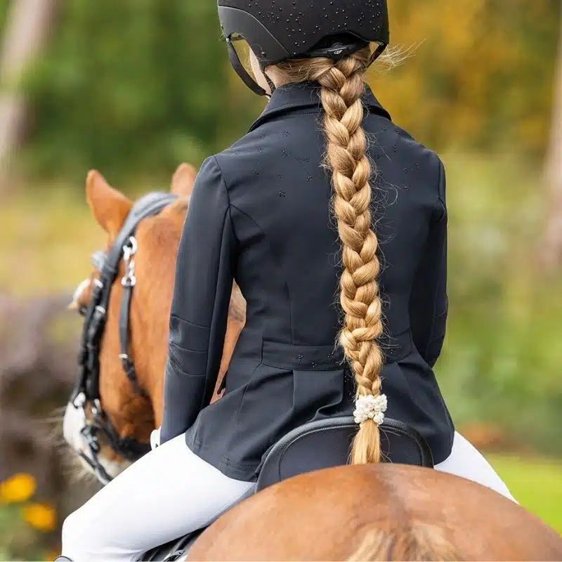 vue de dos d'une jeune cavalière portant la veste de concours Amilara QHP à cheval