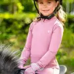 Polo d'équitation Lucky Start Junior QHP rose porté par une jeune cavalière Polo d'équitation Lucky Start Junior QHP rose porté par une jeune cavalière