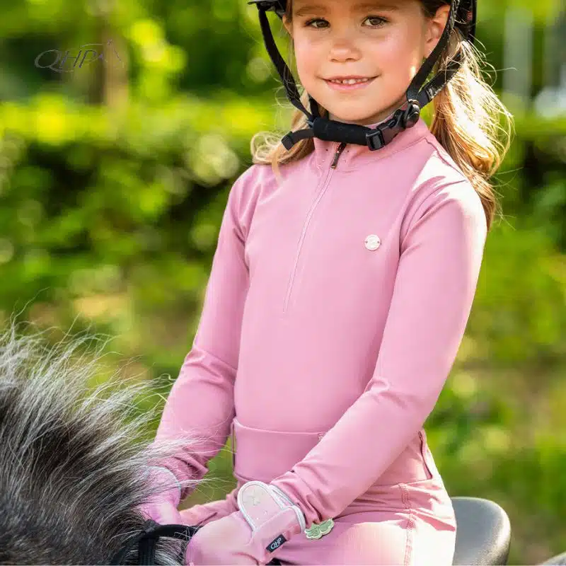 Polo d'équitation Lucky Start Junior QHP rose porté par une jeune cavalière