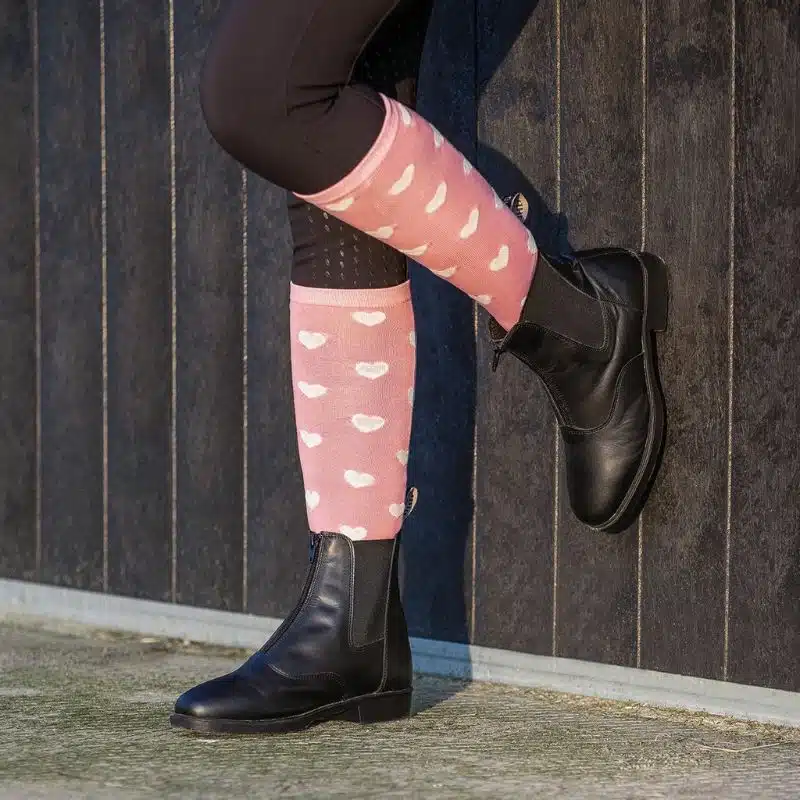 Cavalière portant des chaussettes d’équitation hautes rose poudré avec motifs cœurs