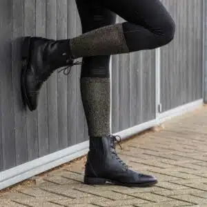 Chaussettes d’équitation Merry Christmas noire et or pailletée portée par une cavalière Cavalière portant une chaussette d’équitation noire et or pailletée QHP