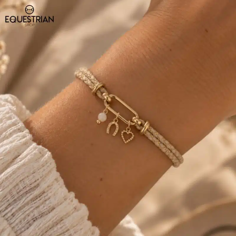 Bracelet Epona EQUESTRIAN SHOP beige porté au poignet, avec perle naturelle, fer à cheval et charm cœur
