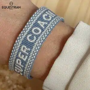 Bracelet Super Coach EQUESTRIAN SHOP bleu ciel avec broderie blanche porté au poignet