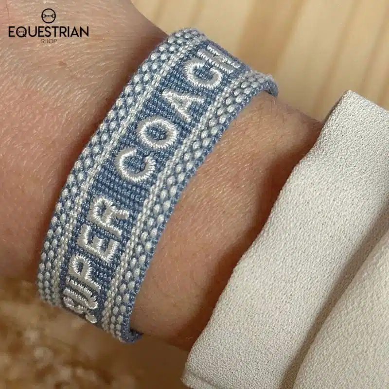 Bracelet Super Coach EQUESTRIAN SHOP bleu ciel avec broderie blanche porté au poignet